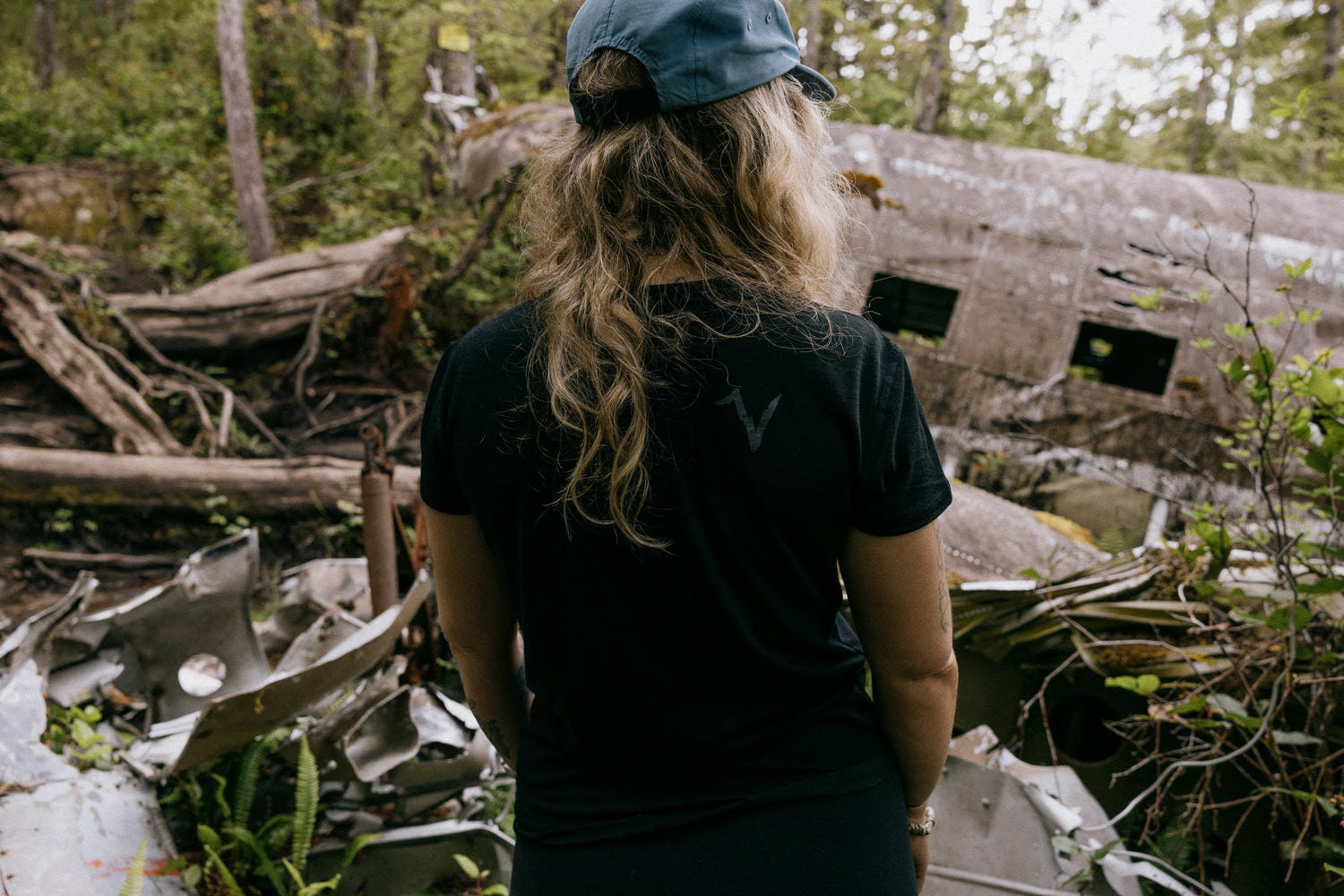 Woman wearing VOORMI Short Sleeve Tech Tee with plane crash in background